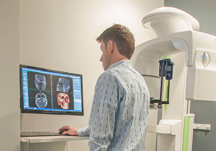 Dentist reviewing panoramic x-rays next to cone beam scanner